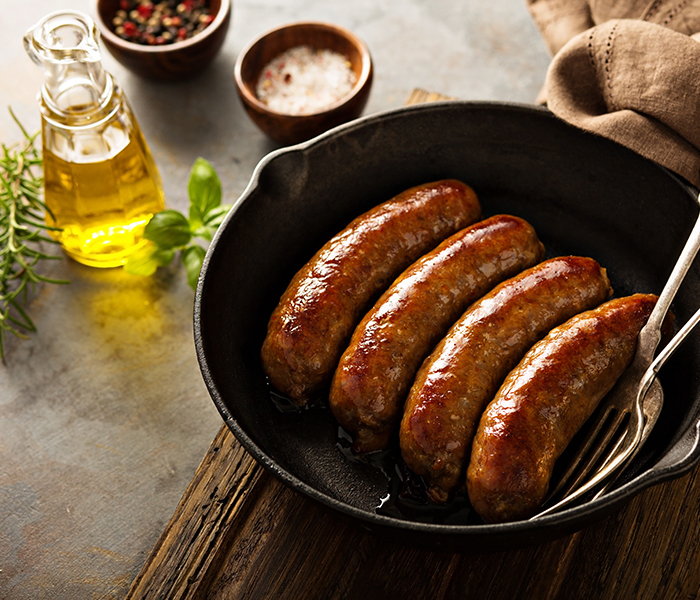 White wine infused sausage in a cask iron skillet with ingredients on a table 