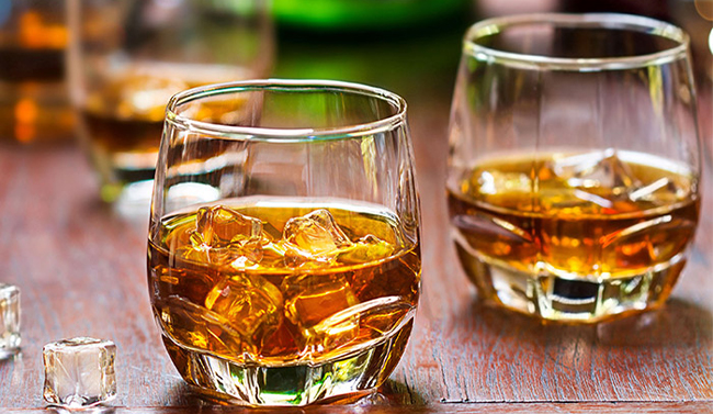 Bottle of whiskey being poured into a glass with ice