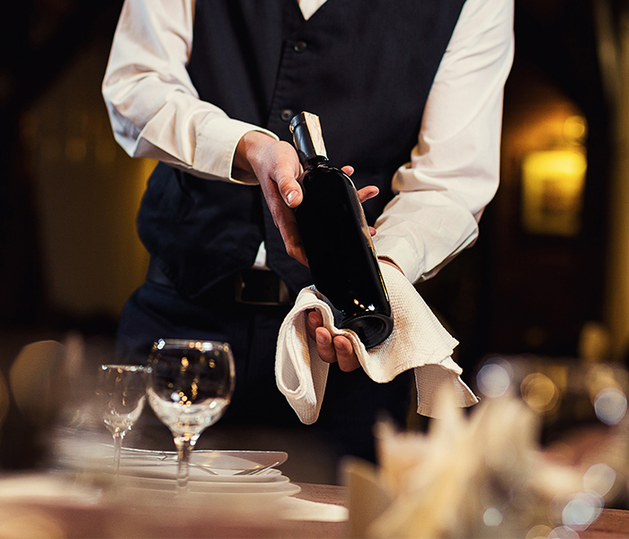 A server holding a bottle of wine